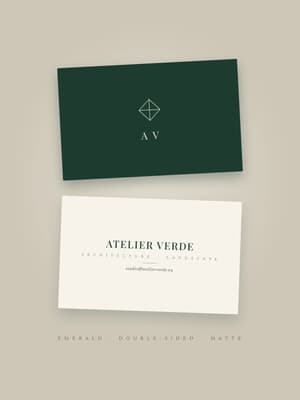 Double-sided business cards in emerald green and ivory with an architectural monogram